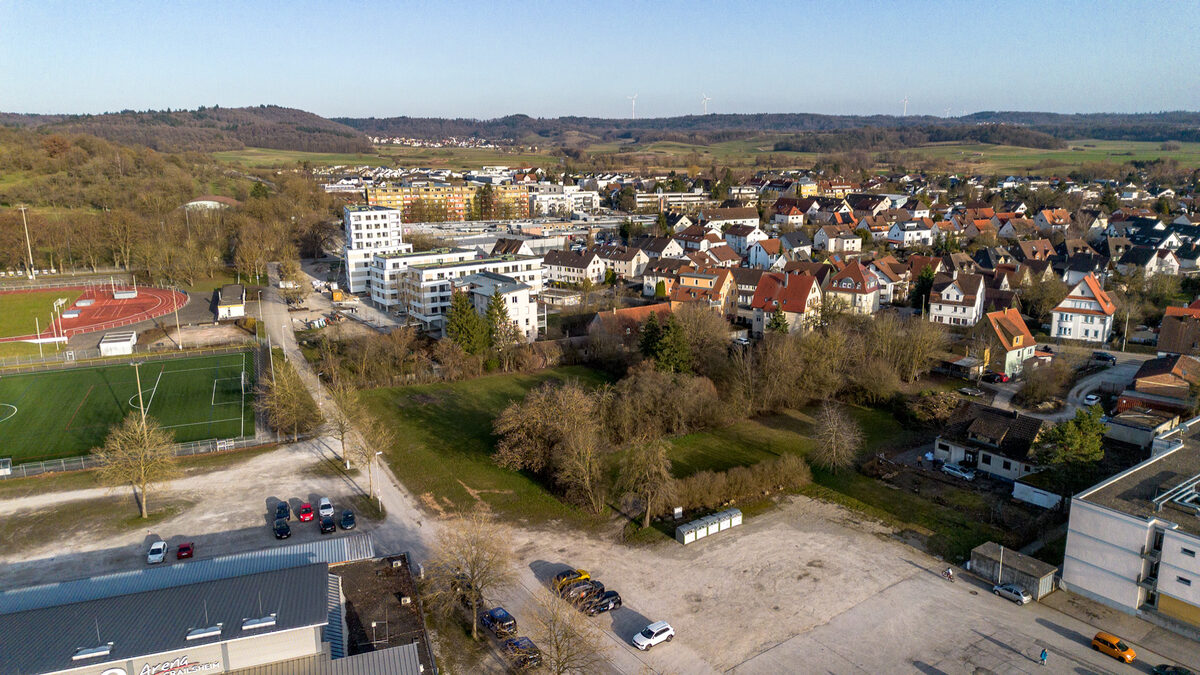 Luftbild: Grünfläche mit Bäumen am Volksfestplatz vor Baubeginn, dahinter Wohnhäuser von Crailsheim
