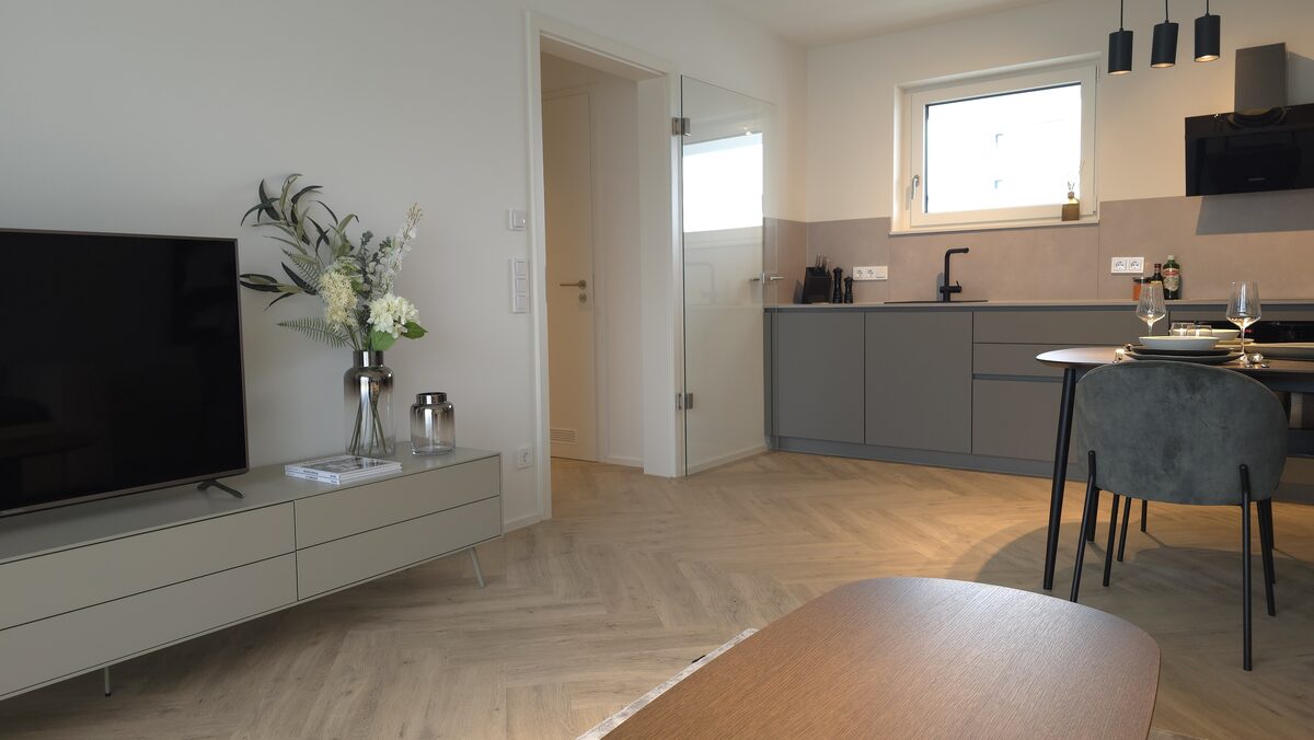 Musterwohnung: Wohnbereich mit Fischgrätparkett, Blick zur Küche